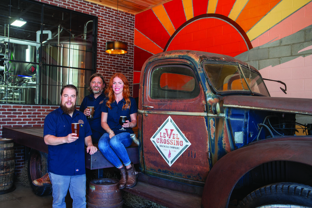 Three Level Crossing Brewery Co. employees pose with drinks in the brewery