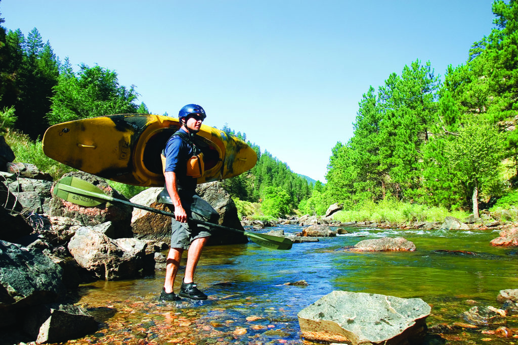 Man stands with kayan in Poudre River Whitewater Park